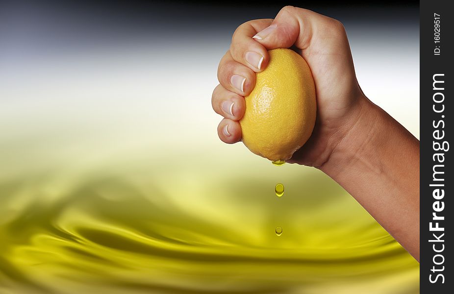 Hand squeezing fresh lemon with juice dripping of hand and lemon