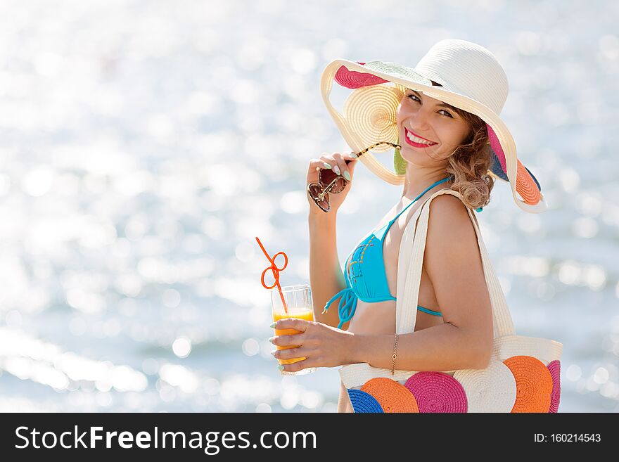 Girl in a hat blue bikini and a glass of juice on vacation. Girl in a hat blue bikini and a glass of juice on vacation