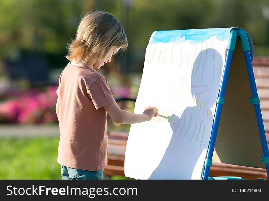 A Preschool Boy Draws With Paints