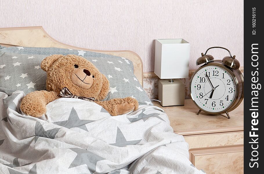 A Teddy bear sleeping in the bed in the bedroom