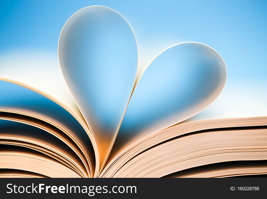 Book Pages On Blue Background, Glowing Heart Formed By Book