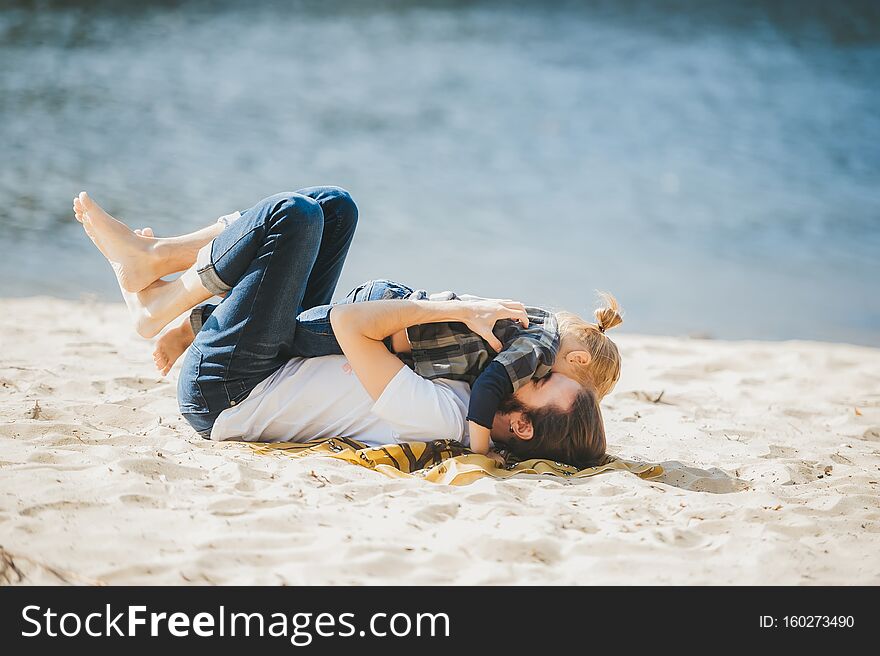 Side view of a happy father playing with young son at the sandy beach. Side view of a happy father playing with young son at the sandy beach