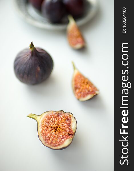 One whole fig and the other sliced lie on a white table
