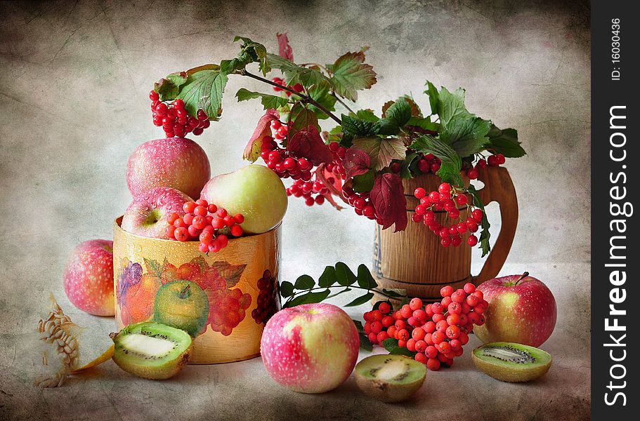 The branches of viburnum cost in a vase alongside apples and kiwi