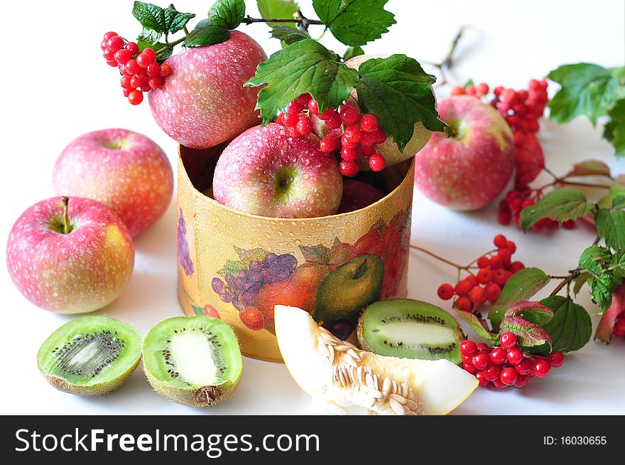 The branch of viburnum lies on apples, by the row of lobule of kiwi, melons. The branch of viburnum lies on apples, by the row of lobule of kiwi, melons