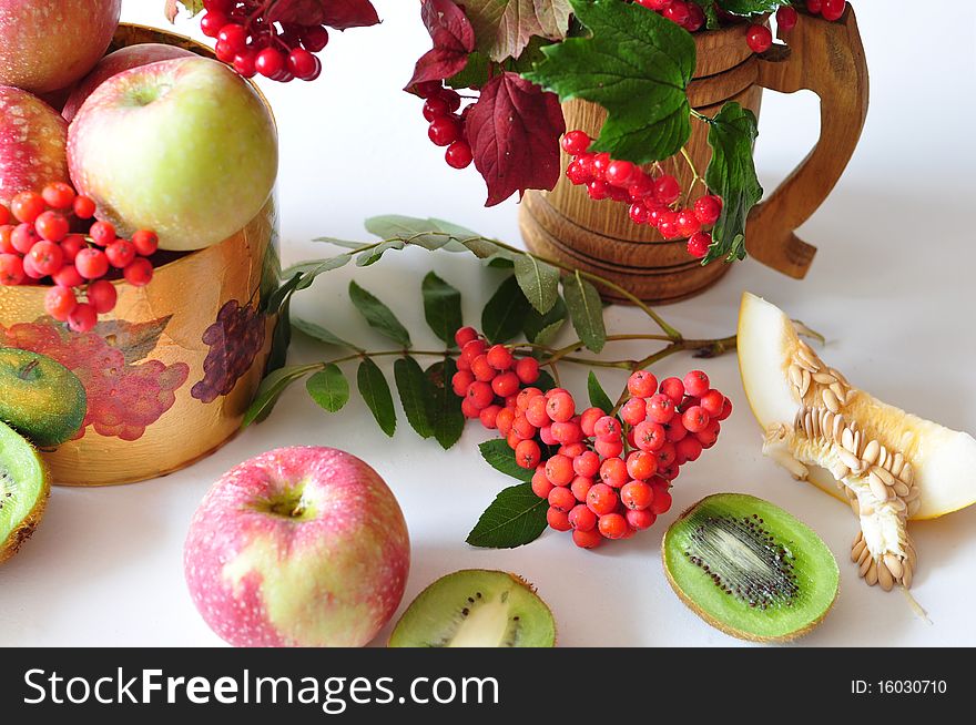 The branch of viburnum lies on apples, by the row of lobule of kiwi, melons. The branch of viburnum lies on apples, by the row of lobule of kiwi, melons