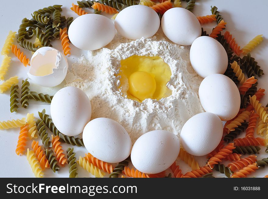 The broken egg lies in a flour, alongside many white eggs and coloured vermicelli. The broken egg lies in a flour, alongside many white eggs and coloured vermicelli