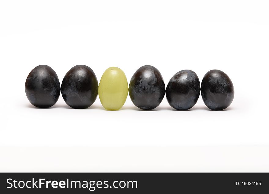 Few red and one green grapes berries standing in a row. Isolated on white background with clipping path. Few red and one green grapes berries standing in a row. Isolated on white background with clipping path