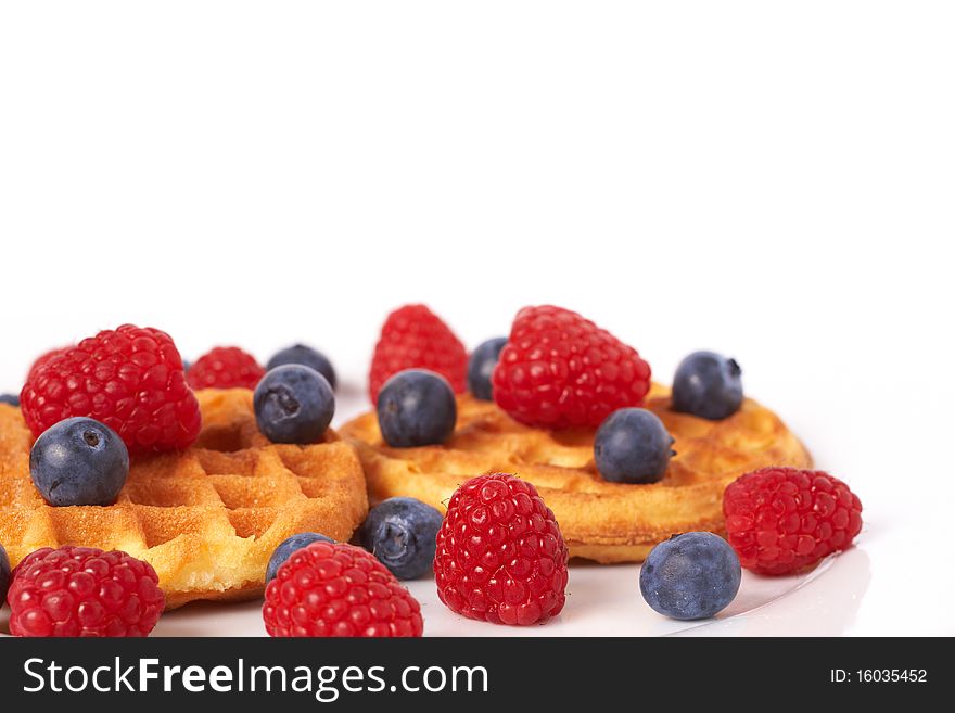 Belgian waffles with fresh raspberries and blueberries on white plate. Belgian waffles with fresh raspberries and blueberries on white plate