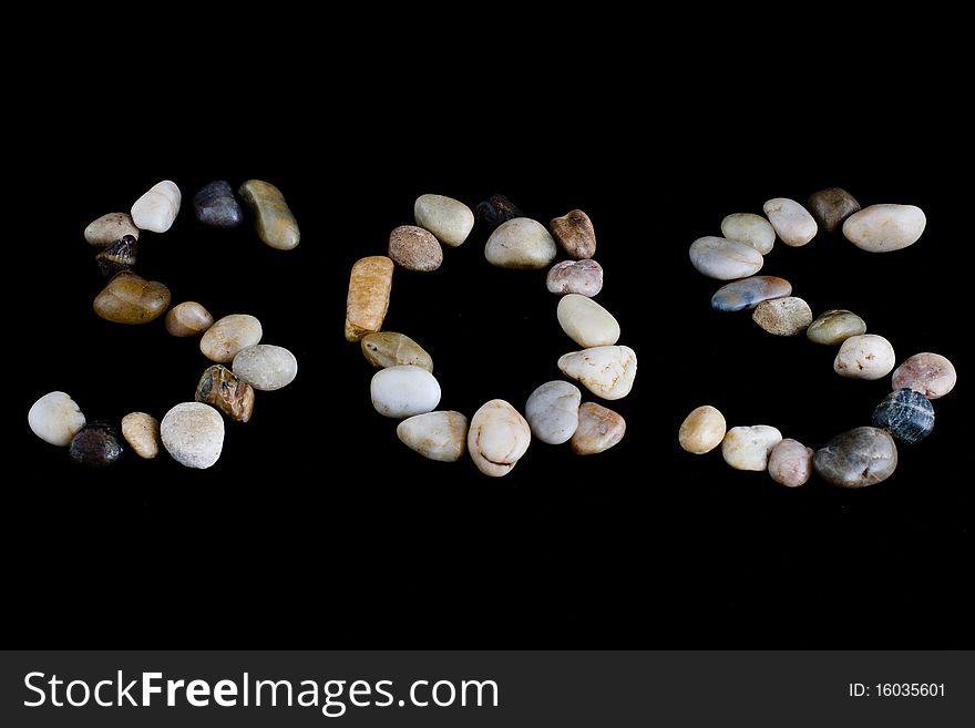 Photo of SOS on black background. Made of pebbles. Photo of SOS on black background. Made of pebbles.