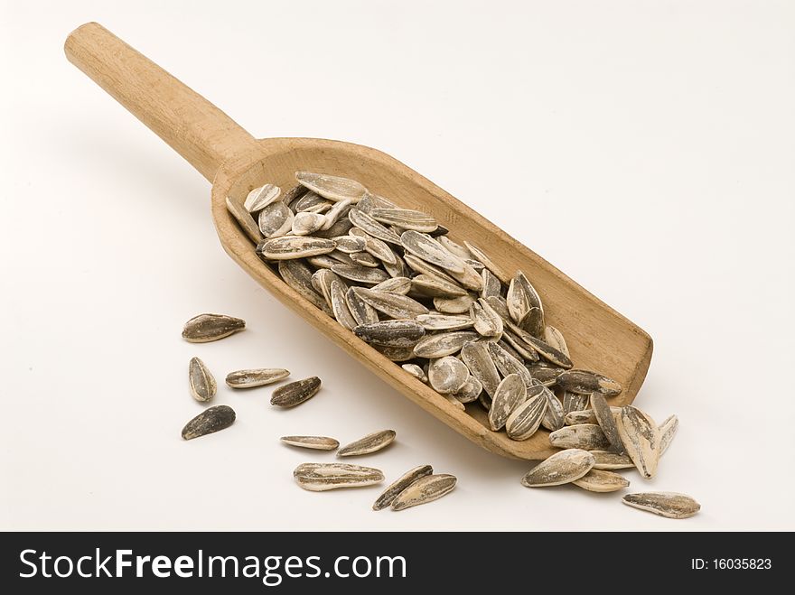 Dried sunflower seeds in a wooden spoon. White background. Dried sunflower seeds in a wooden spoon. White background.