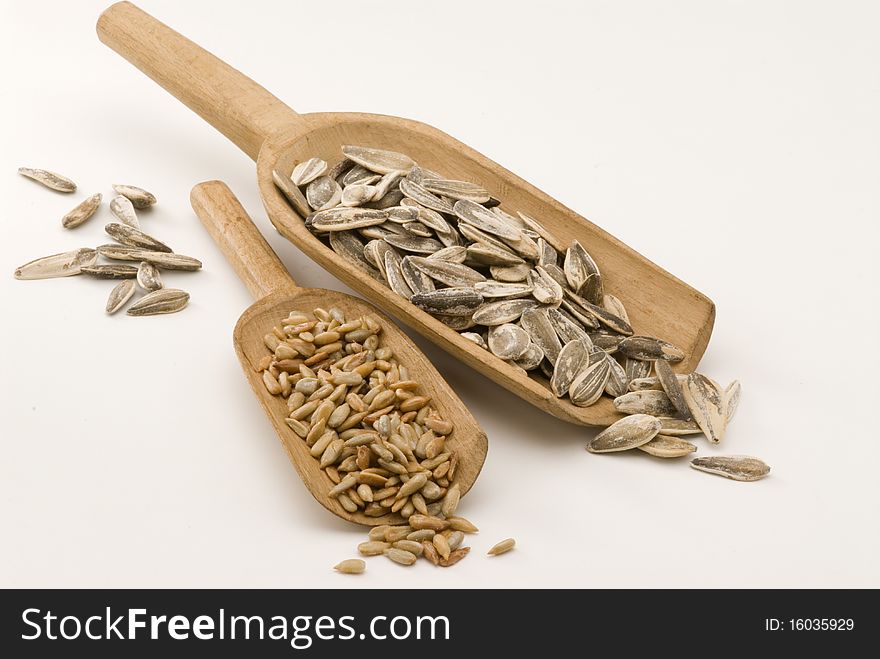 Dried sunflower seeds in wooden spoons. White background. Dried sunflower seeds in wooden spoons. White background.