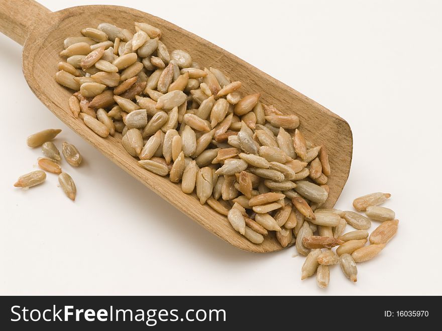 Dried sunflower seeds in a wooden spoon. White background. Dried sunflower seeds in a wooden spoon. White background.