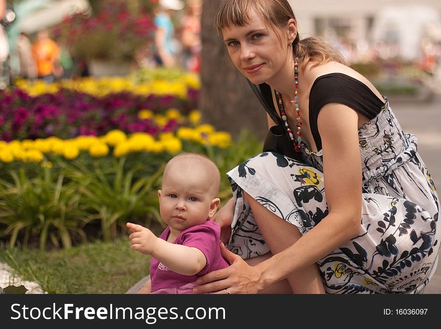 Young mother with her little doughter sitiing near flowers. Young mother with her little doughter sitiing near flowers