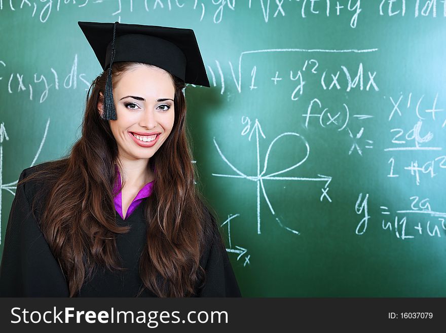 Educational theme: graduating student in academic gown in a classroom. Educational theme: graduating student in academic gown in a classroom.