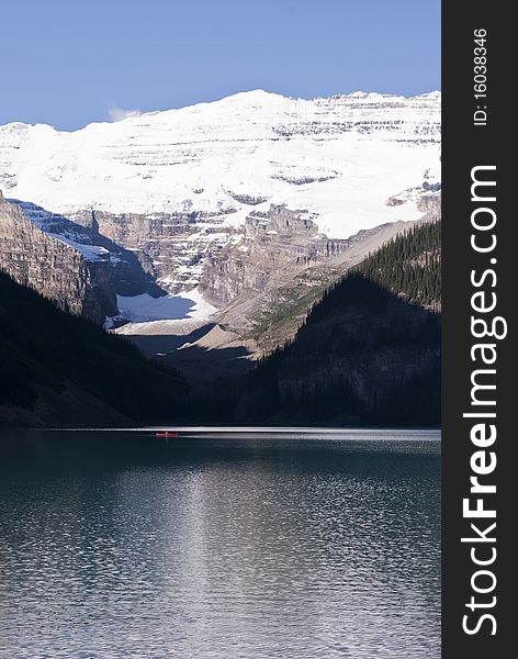 A beautiful blue lake with a person and its canoe under an imponent glacier in the Canadian Rockies. A beautiful blue lake with a person and its canoe under an imponent glacier in the Canadian Rockies