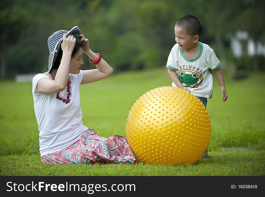 Mother and son play ball in grass