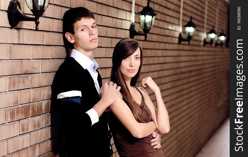 Young pair stay near brick wall