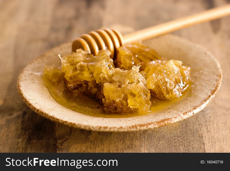 Honeycombs on a plate wooden honey stick. Honeycombs on a plate wooden honey stick