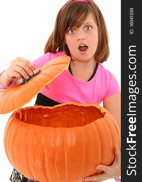 Beautiful 10 year old girl with giant empty pumpkin and surprised expression over white background. Beautiful 10 year old girl with giant empty pumpkin and surprised expression over white background.