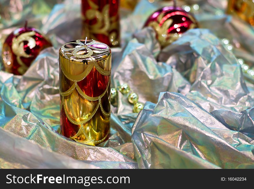 Christmas a background. A decorative candle on a silvery fabric. Christmas a background. A decorative candle on a silvery fabric