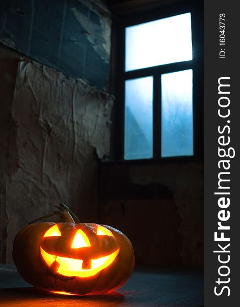 Halloween pumpkin in night on old wood room with blue window