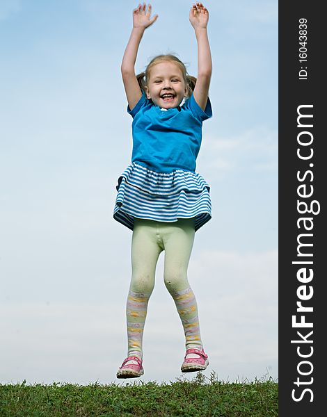 Little girl jump om grass under sky