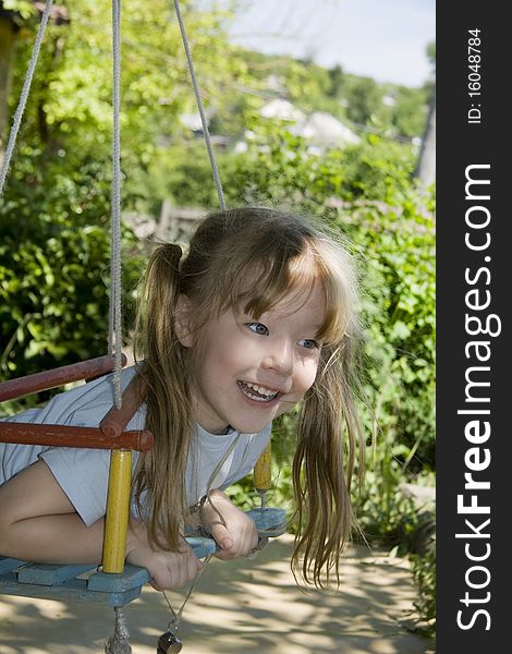 Cheerful little girl shakes on a swing. Cheerful little girl shakes on a swing