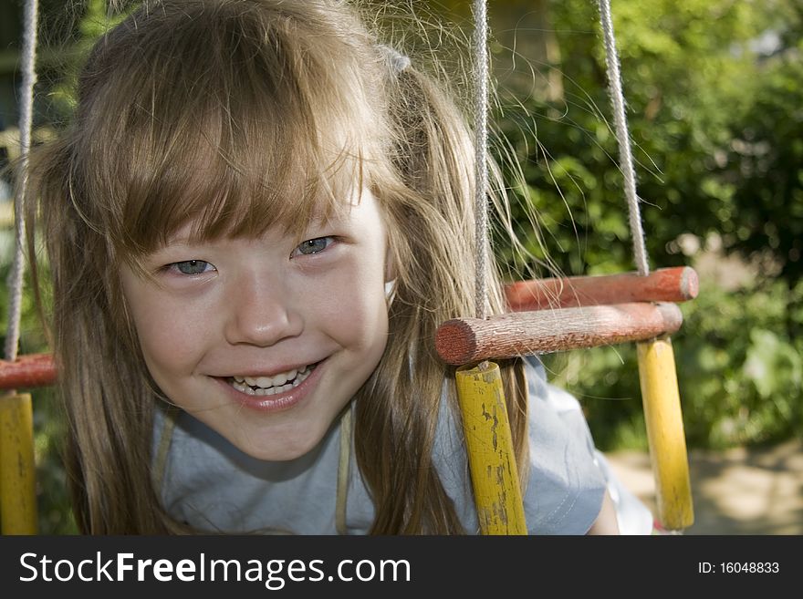 Cheerful little girl shakes on a swing. Cheerful little girl shakes on a swing