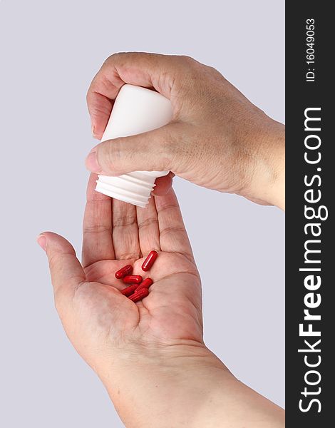 Hands Of Old Woman Taking Pills Isolated With Gray Background