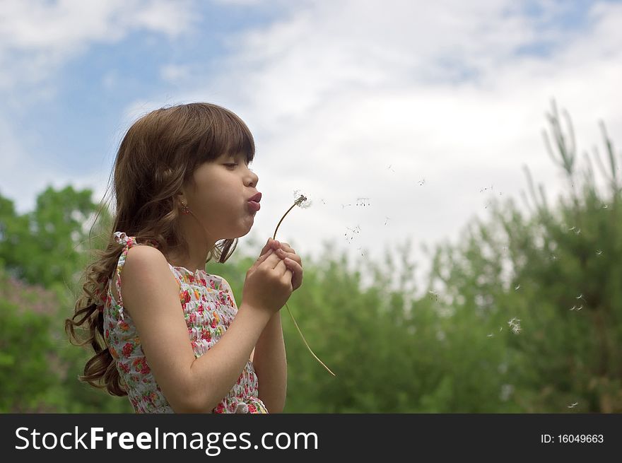 Beautiful young girl blow dandelion outdoor