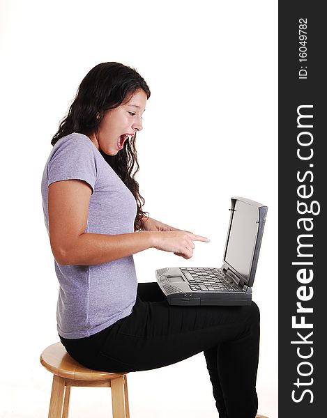 An happy young woman with a laptop on her lap, sitting on a chair in black jeans and is surprised what she sees on the screen, for white background. An happy young woman with a laptop on her lap, sitting on a chair in black jeans and is surprised what she sees on the screen, for white background.