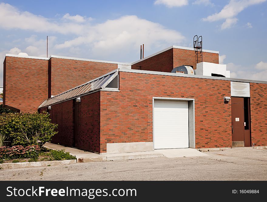 Exterior of brick industrial building, with loading dock, shot on a bright sunny day.