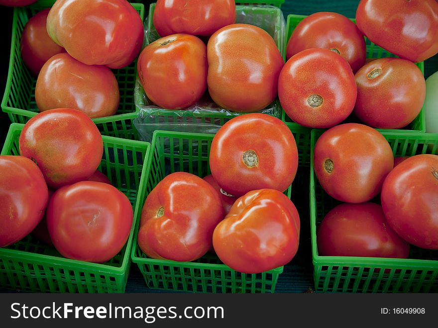 Close up of red tomatoes in green baskets, taken in a farmers market. Close up of red tomatoes in green baskets, taken in a farmers market