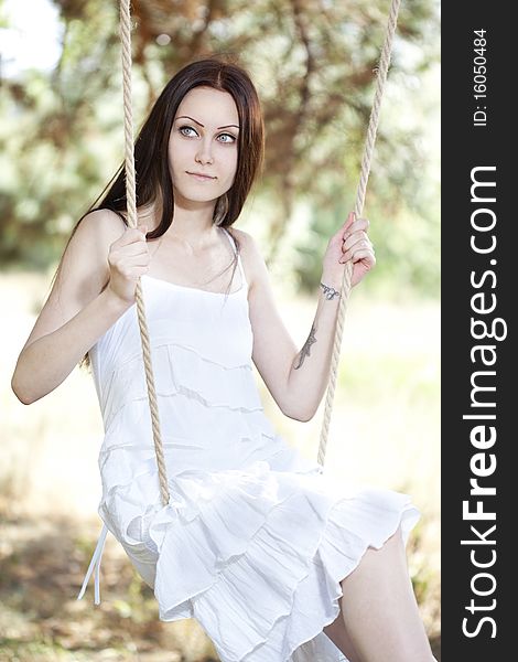 Young woman swinging outdoor in summer