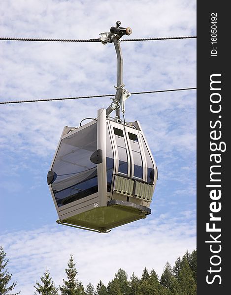 Cable car on a cable way against a cloudy blue sky. Cable car on a cable way against a cloudy blue sky