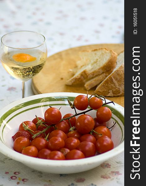 Mediterranean tomatoes appetizer with bread and white wine on set table.