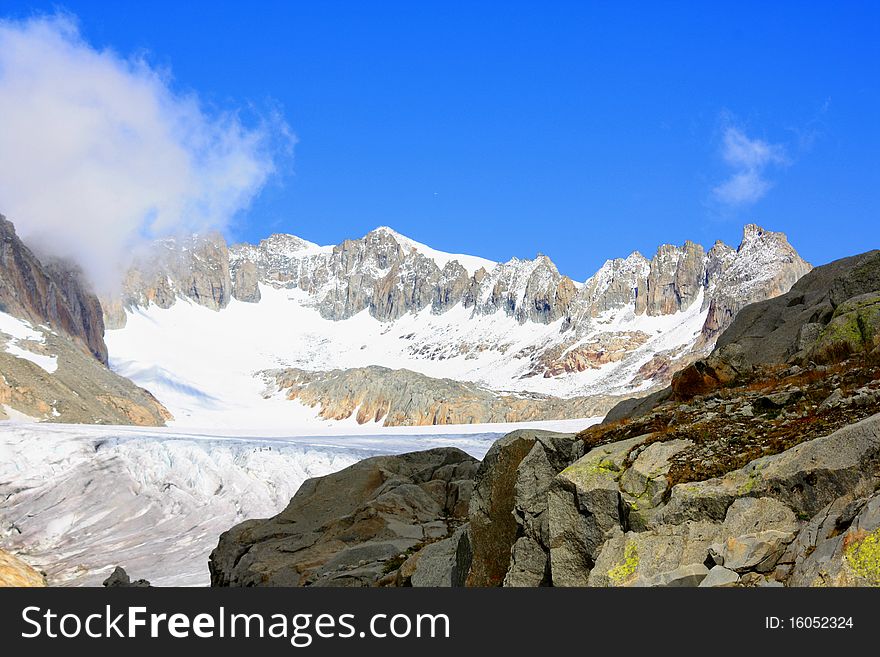 A snow capped mountain in Switzerland overlooking a glacier and a rocky hillside. A snow capped mountain in Switzerland overlooking a glacier and a rocky hillside