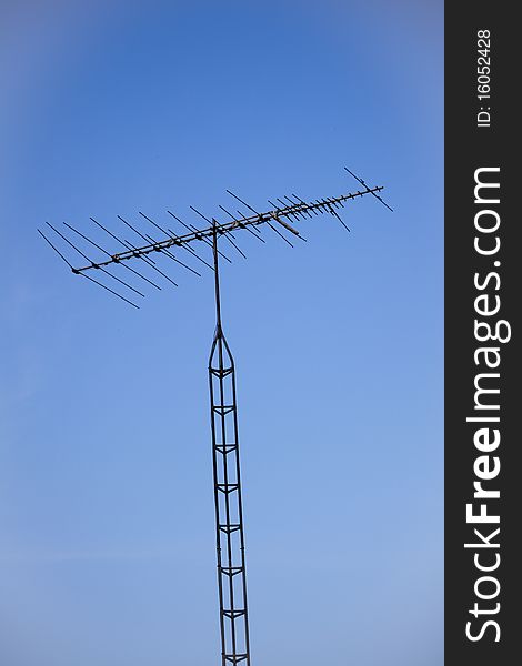 Old fashioned analog TV antenna and tower, shot against a deep blue sky, almost a silhouette. Old fashioned analog TV antenna and tower, shot against a deep blue sky, almost a silhouette