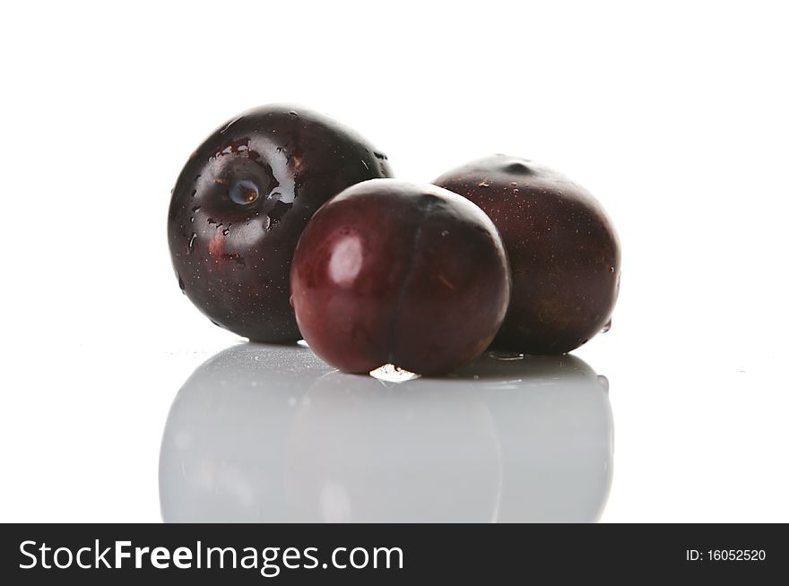 Three big fresh plums with reflection isolated on white