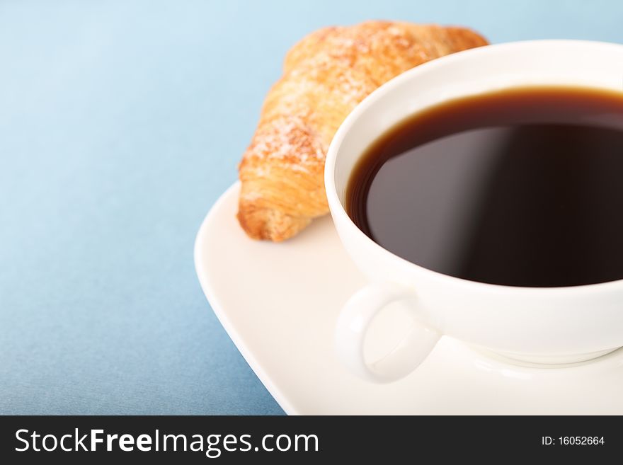 Coffee and croissant on the blue background