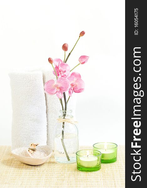 Composition of Pink orchid, towel and two candles .