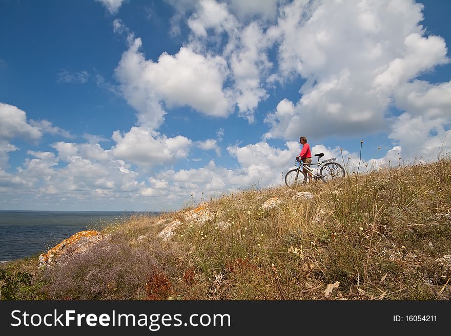 Women with bike on meadow on sky background. Women with bike on meadow on sky background