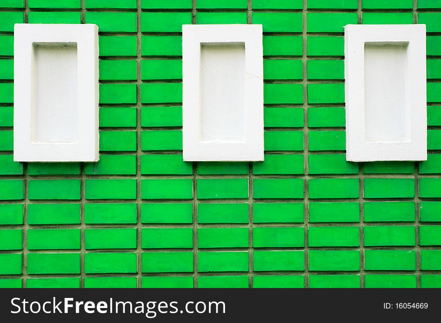 Green brick wall with three white rectangle blocks