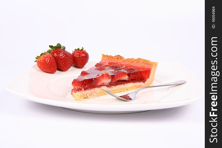 Piece of Strawberry Tart on a plate decorated with strawberries, and a fork