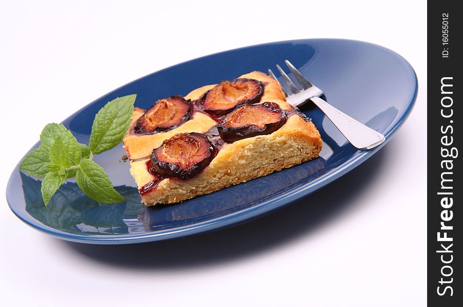 Piece of Plum Pie on a blue plate decorated with a mint twig