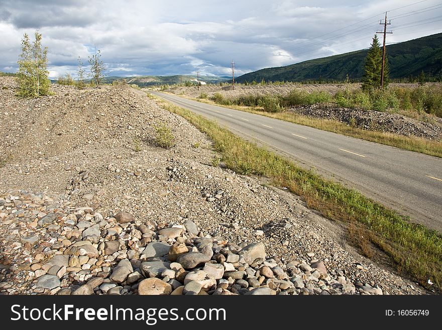 Piles of dredge rock and gravel line the highway into Dawson City, Yukon. Piles of dredge rock and gravel line the highway into Dawson City, Yukon
