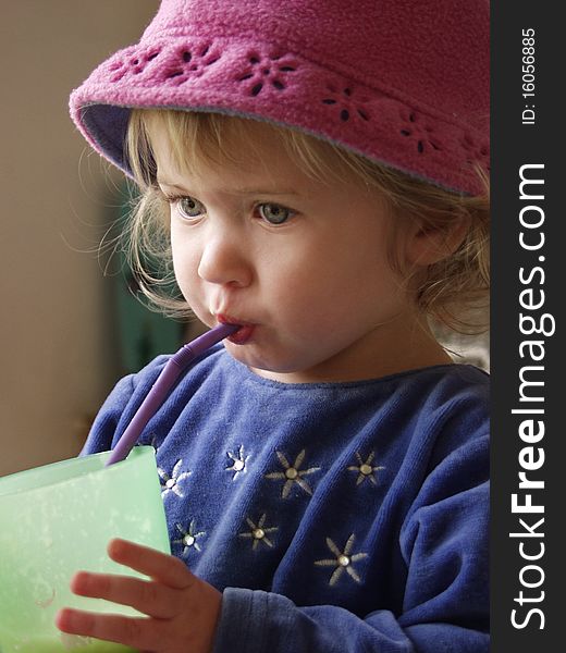 20 month old girl in fleece hat, drinking from straw. 20 month old girl in fleece hat, drinking from straw