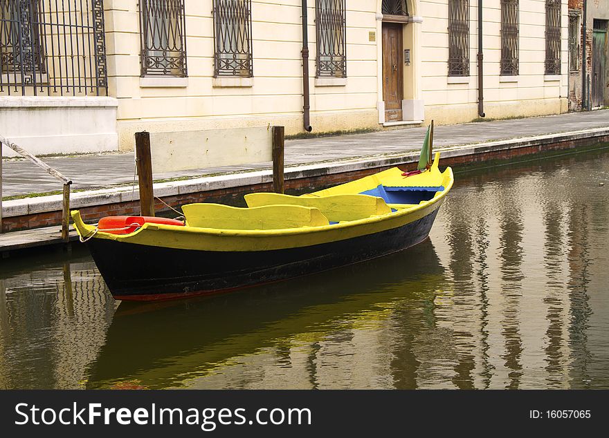 Blue and yellow boat along a canal of Comacchio