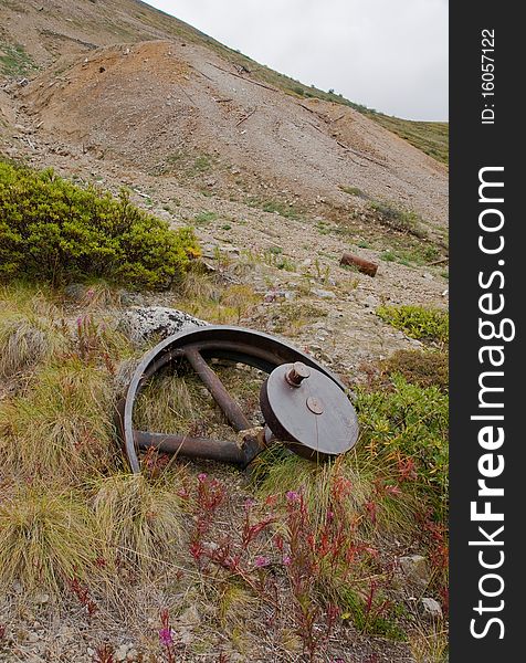 A large gear wheel lies abandoned near mining tailings in Yukon Territory. A large gear wheel lies abandoned near mining tailings in Yukon Territory